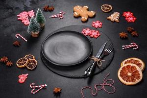 Christmas table setting with empty black ceramic plate, fir tree and black accessories photo
