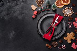 Christmas table setting with empty black ceramic plate, fir tree and black accessories photo