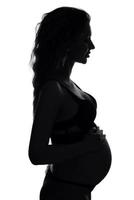 una joven mujer blanca embarazada tiene nueve meses de embarazo en un fondo brillante foto