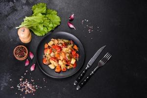 Vegetable stew or ratatouille with eggplant, tomatoes, sweet and hot peppers, onions, carrots and spices in plate photo