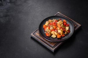Vegetable stew or ratatouille with eggplant, tomatoes, sweet and hot peppers, onions, carrots and spices in plate photo