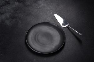 Black plate on a black background. Flat lay, top view, copy space photo