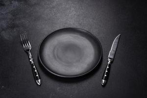 Black plate on a black background. Flat lay, top view, copy space photo