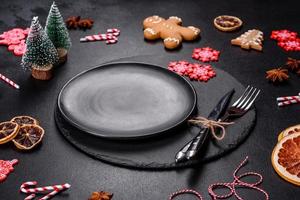 Christmas table setting with empty black ceramic plate, fir tree and black accessories photo