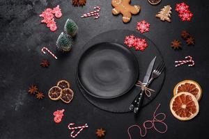 Christmas table setting with empty black ceramic plate, fir tree and black accessories photo