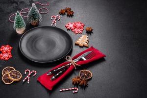 Christmas table setting with empty black ceramic plate, fir tree and black accessories photo