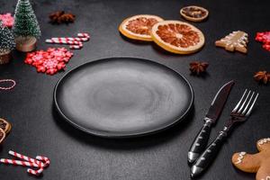 Christmas table setting with empty black ceramic plate, fir tree and black accessories photo