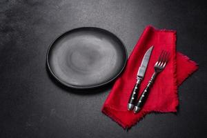 Christmas table setting with empty black ceramic plate, fir tree and black accessories photo