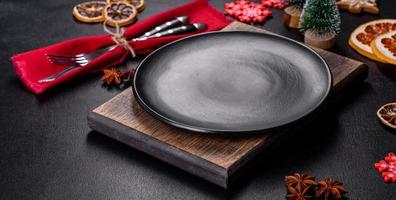 Christmas table setting with empty black ceramic plate, fir tree and black accessories photo