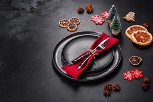 Christmas table setting with empty black ceramic plate, fir tree and black accessories photo