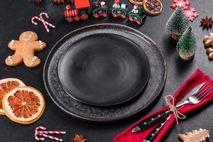 Christmas table setting with empty black ceramic plate, fir tree and black accessories photo