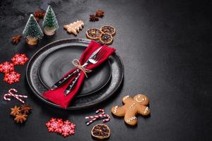 Christmas table setting with empty black ceramic plate, fir tree and black accessories photo