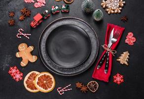 Christmas table setting with empty black ceramic plate, fir tree and black accessories photo