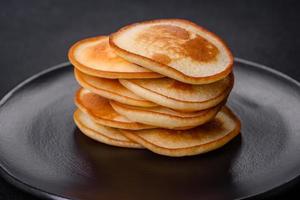 deliciosos panqueques frescos en un plato negro sobre un fondo de hormigón oscuro foto