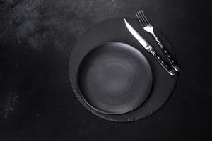 Black plate on a black background. Flat lay, top view, copy space photo