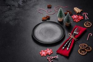 Christmas table setting with empty black ceramic plate, fir tree and black accessories photo
