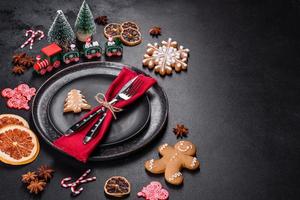 Christmas table setting with empty black ceramic plate, fir tree and black accessories photo