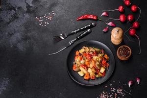 Vegetable stew or ratatouille with eggplant, tomatoes, sweet and hot peppers, onions, carrots and spices in plate photo