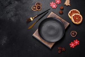 Christmas table setting with empty black ceramic plate, fir tree and black accessories photo
