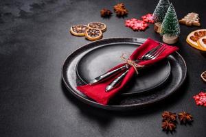 Christmas table setting with empty black ceramic plate, fir tree and black accessories photo