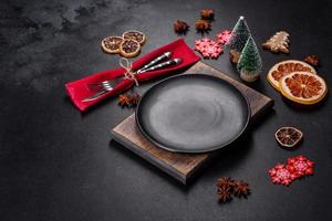 Christmas table setting with empty black ceramic plate, fir tree and black accessories photo