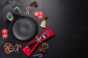 Christmas table setting with empty black ceramic plate, fir tree and black accessories photo
