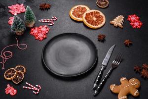 Christmas table setting with empty black ceramic plate, fir tree and black accessories photo