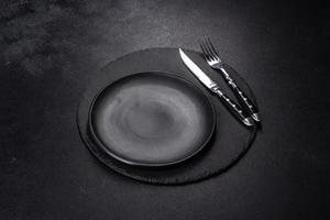 Black plate on a black background. Flat lay, top view, copy space photo