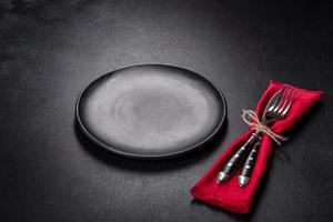 Christmas table setting with empty black ceramic plate, fir tree and black accessories photo