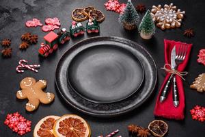 Christmas table setting with empty black ceramic plate, fir tree and black accessories photo