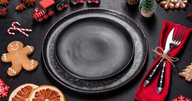 Christmas table setting with empty black ceramic plate, fir tree and black accessories photo