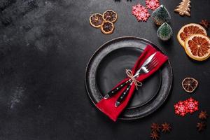 Christmas table setting with empty black ceramic plate, fir tree and black accessories photo