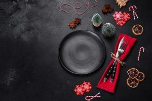 Christmas table setting with empty black ceramic plate, fir tree and black accessories photo