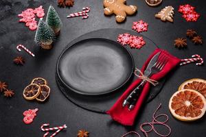 Christmas table setting with empty black ceramic plate, fir tree and black accessories photo