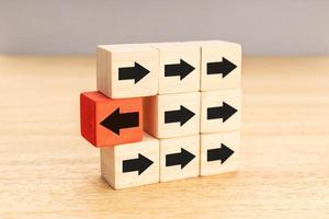 Think different, unique or independent concept. Arrow pointing the opposite way disruptive from other arrows on wooden blocks photo