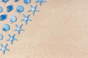 Summer background with blue seashell pattern on beach sand background. Copy space. Top view photo