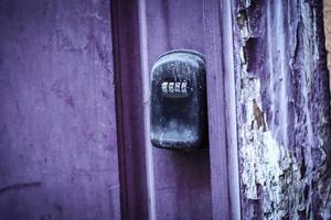 Cerradura de puerta codificada mecánica negra antigua en puerta púrpura y pared de yeso pelado foto