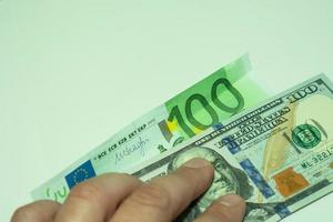 100 dollars and one hundred euros on a light green background are pressed with fingers. photo
