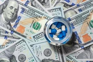 Capsule pills in a plastic jar on money, top view. photo