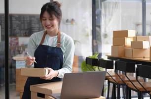 Shipping shopping online ,young start up small business owner writing address on cardboard box at workplace.small business entrepreneur SME or freelance asian woman working with box at home photo