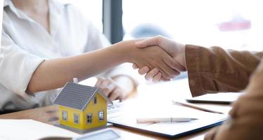 Real estate broker agent and customer shaking hands after signing contract documents for realty purchase, Bank employees congratulate, Concept mortgage loan approval. photo