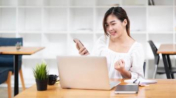 Young asian businesswoman beautiful charming smiling and using on mobile phone in the office. photo