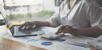 empresa de auditoría, la secretaria del inspector financiero de las mujeres de negocios informa sobre el cálculo, control del saldo. El servicio de impuestos internos inspecciona el documento de cheques con una computadora portátil y una calculadora. foto