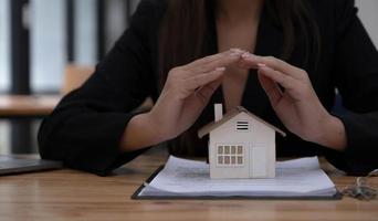 Property insurance and security concept. Protecting gesture of man and symbol of the house. Wide banner composition with office in background. photo