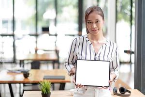 Mockup image of a smiley Asian beautiful woman holding and showing black  mobile phone with blank white screen. photo