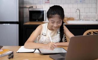 Asian girl student online learning class study online video call zoom teacher, Happy girl learn english language online with laptop at home.New normal.Covid-19 coronavirus.Social distancing.stay home photo