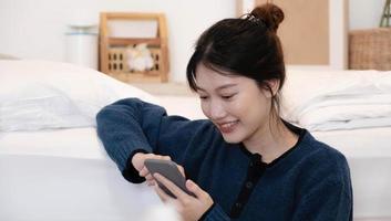 Beautiful woman using a smart phone in the morning on the bed at home photo