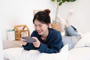 Beautiful woman using a smart phone in the morning on the bed at home photo