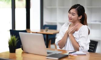 Happy young asian businesswoman sitting on her workplace in the office. Young woman working at laptop in the office. photo