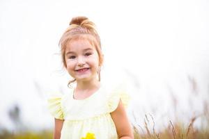 Portrait of a cute girl in field with a wild flower. Childhood, holidays in the country, freedom and carelessness. Summer time. International Children Day. Mosquito repellent, cottage core. Copy space photo